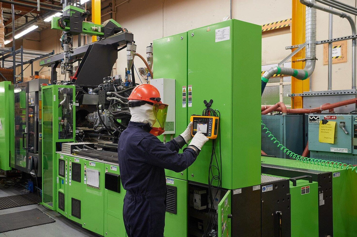 Tekniker i beskyttelsesudstyr anvender Fluke 1775 Power Quality Analysator på et industrielt elpanel.