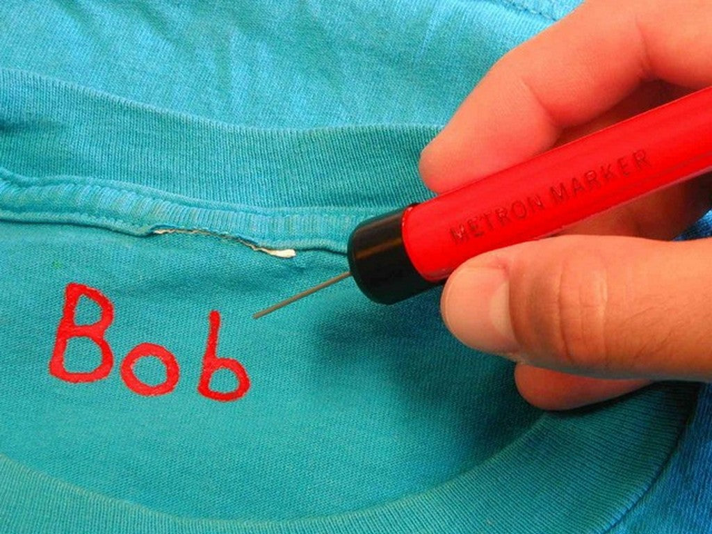 Metron mærkepen rød permanent. Bruger skriver "Bob" på blå t-shirt.