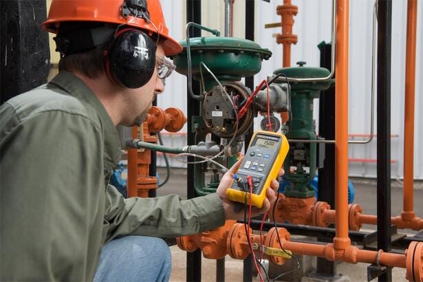Tekniker anvender Fluke 719-30G elektrisk trykkalibrator i et industrielt procesmiljø til kalibrering.