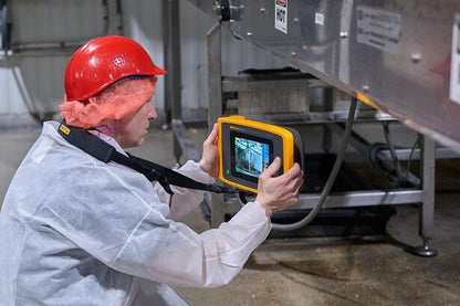 Tekniker i beskyttelsestøj bruger Fluke ii905 Sonic Industrial Imager til at scanne et produktionsanlæg.