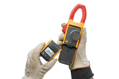 Tekniker med sikkerhedshandsker fjerner det trådløse display fra et Fluke 381 tangamperemeter.